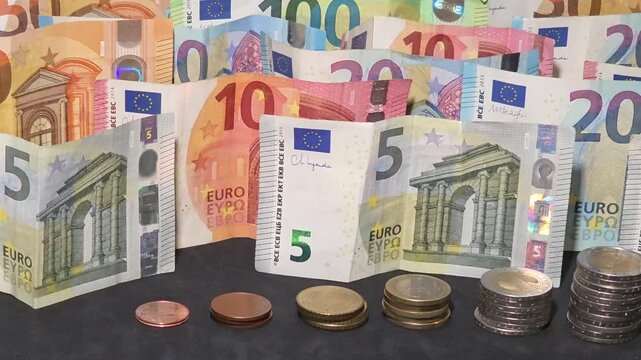 High angle panning shot of euro bills and coin stacks showing growth
