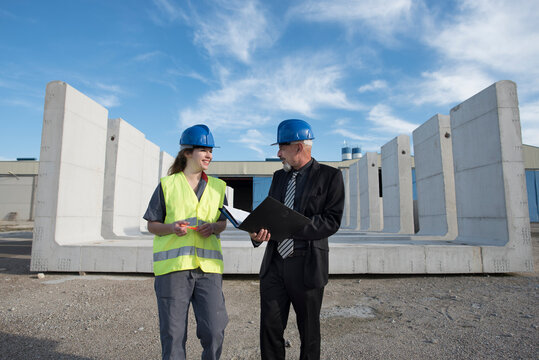 Woman worker and construction manager speak amicably near concrete structures in Cordoba, Spain.