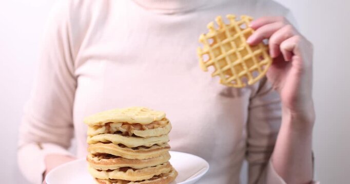 many delicious waffles on a plate for breakfast on a light background
