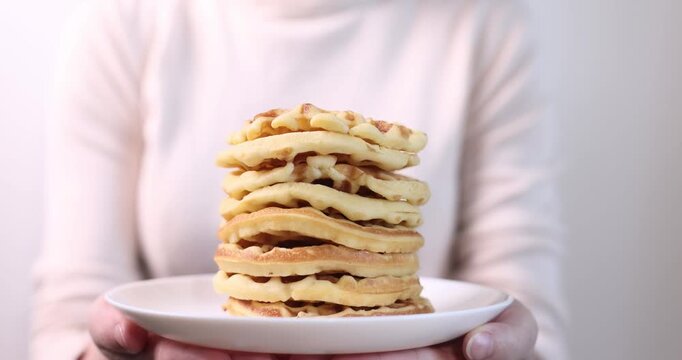 many delicious waffles on a plate for breakfast on a light background
