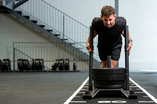 Determined man pushing heavy sled during functional training