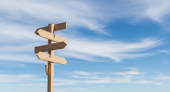 Wooden signpost with multiple blank directional arrows against a blue sky