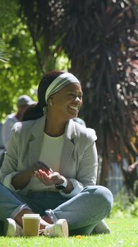 Vertical video: Offering food, woman in blazer, jeans feeding pigeons in sunlit park to relax