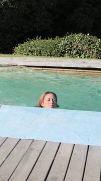 Vertical video: Running jumper jumping into home pool to join friends in swimwear by towel phone