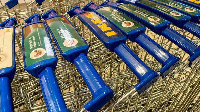Closeup of blue shopping cart handles stacked in a brightly lit supermarket aisle, retail detail for ecommerce marketing and social media, 5 May 2026 Belgrade, Serbia