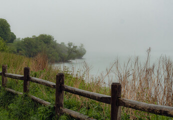 Obraz premium Wooden fence along a misty Lake Ontario shoreline path at Ajax Waterfront Park