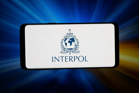 Stuttgart, Germany - 06-10-2026: In this photo illustration, the logo of international police organization Interpol is displayed on a smartphone in front of abstract background on computer screen.
