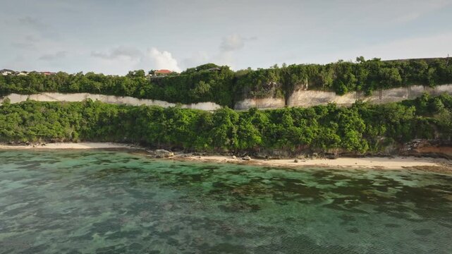 Green Bowl Beach in Bali, dramatic green cliffs, pristine white sand and turquoise waters, an untouched tropical coastline ideal for serene island escape, travel destination. Aerial view drone flight
