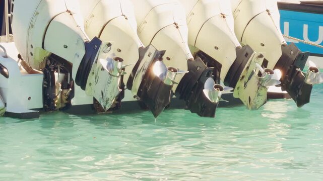 Row Of Boat Outboard Motors Above Clear Turquoise Water In Marina, Marine Transportation And Nautical Industry