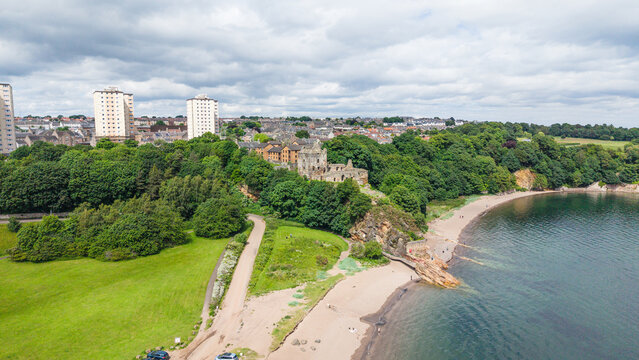 Aerial view of the ruined Ravenscraig Castle standing on a rocky cliff by the sandy beach and coastline in Fife, Scotland