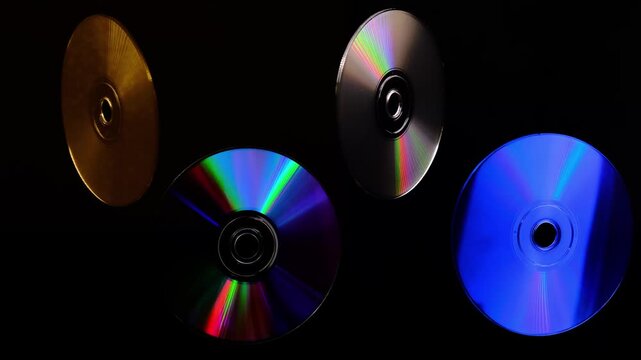 a rotating CD and DVD discs showcasing vibrant rainbow-like colors. Brilliant rainbow diffraction patterns shimmer across the metallic surfaces, creating vivid colors and holographic reflections