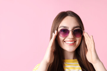 Fototapeta premium Young woman wearing stylish sunglasses on pink background