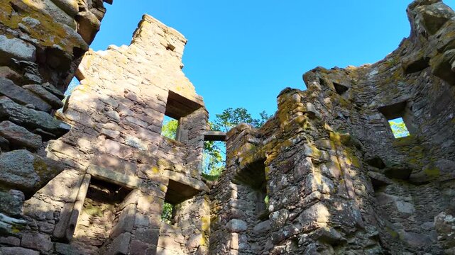 A smooth aerial video rises from Corse Castle in Scotland, revealing stone walls, courtyards, and expanding landscape from top.