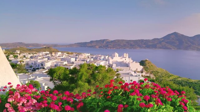 Red geranium flowers on balcony overlooking Plaka village, Milos island