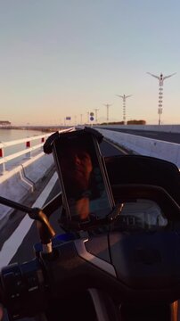 Vertical video. First Person Ride Across Benoa Toll Road Near Bandara Ngurah Rai With Scooter Handlebars And Coastal Highway At Sunrise