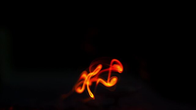 Swirling red incense smoke rising on black background