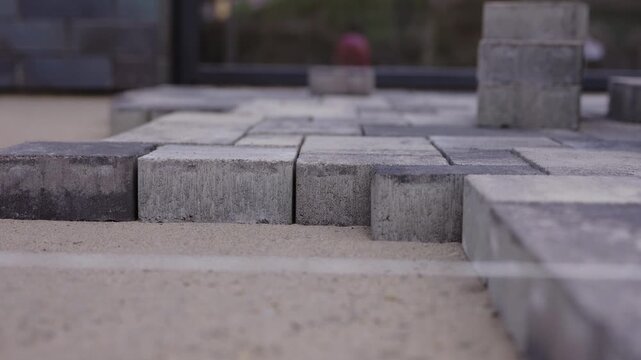Worker laying concrete paving blocks during pavement installation