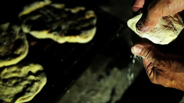 Experienced baker hands kneading traditional bread dough outdoors at night