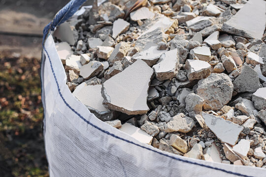 Construction rubble collected in large industrial bag. Demolition waste and broken concrete pieces. Building renovation background. Recycling and construction debris management concept.