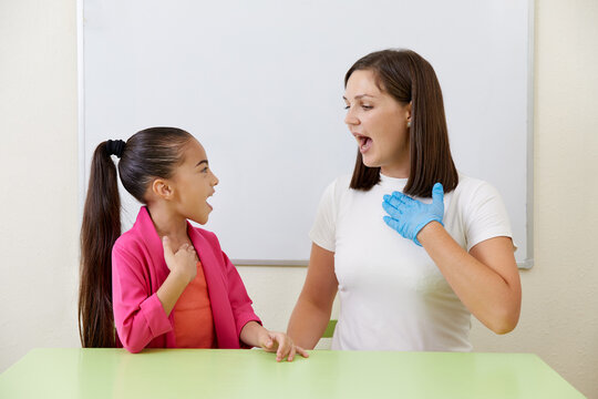Speech therapist working with girl training pronunciation