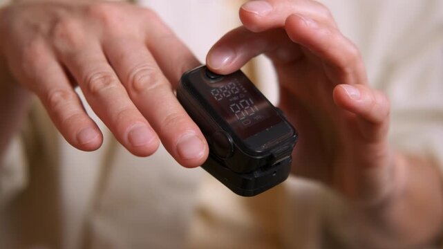 Doctor measuring blood oxygen saturation with pulse oximeter. Close-up of a medical professional attaching a fingertip pulse oximeter to a patient's hand to monitor vital signs, checking oxygen level