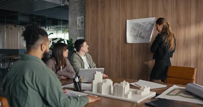 A team gathers in an office to review a presentation about project plans and share ideas among members