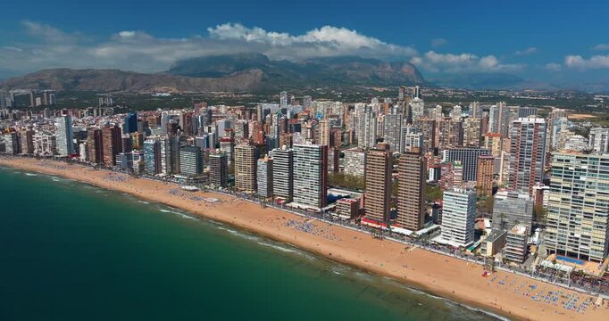 Benidorm full beachfront aerial panorama Spain Alicante Levante Poniente beaches skyscrapers Mediterranean summer drone mountain clouds tourism resort slow motion coastal skyline wide destination