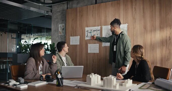Group of people talks about their project in a modern office setting while sharing ideas and looking at charts
