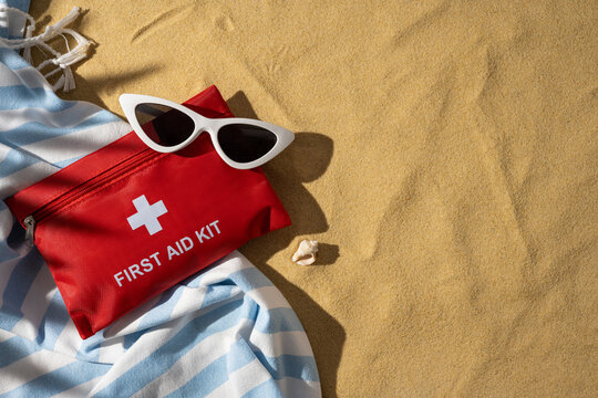 First aid kit and sunglasses on beach towel for travel safety and summer health essentials