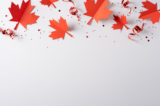 Red paper maple leaves and curled ribbons for Canada independence day celebration with confetti and blank space