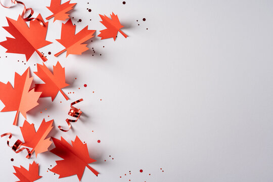 Red paper maple leaves and ribbons celebrating Canada Independence Day with confetti on white background