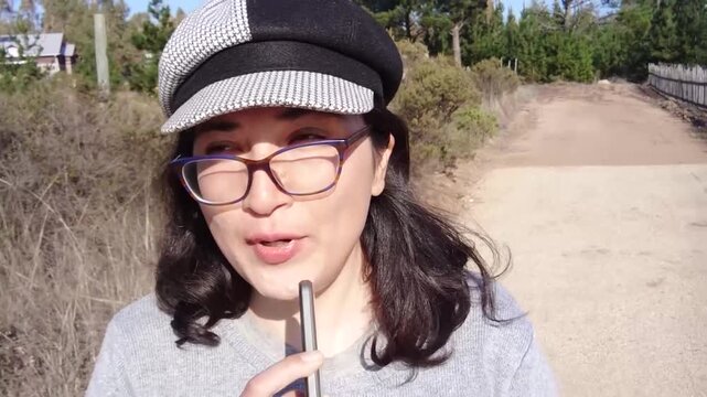 Young Woman Talking to Smartphone Front Camera While Walking Outdoors, Recording Selfie Vlog as Social Media Influencer and Content Creator
