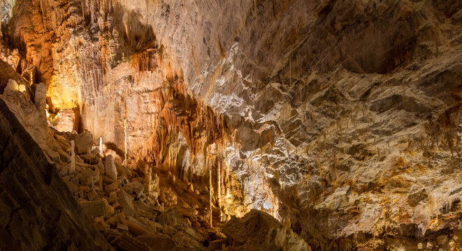 Cabrespine, Occitanie, France: panoramic view inside the Gouffre G&eacute;ant de Cabrespine. Vast limestone cave chamber with illuminated rock walls, stalagmites and underground formations.