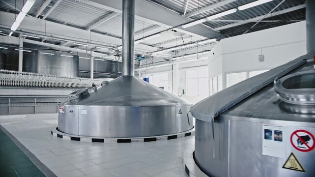 Modern industrial brewery interior with large stainless steel tanks for mashing and fermenting beer, showing the advanced equipment and technology used in alcoholic beverage production