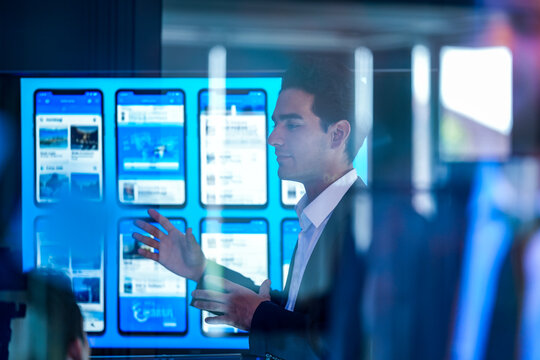 Professional software engineer presenting mobile app UI/UX prototypes and visual node-based logic flow to a development team in a high-tech office.