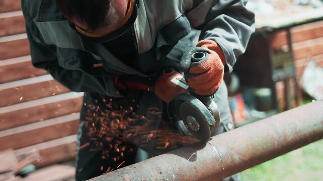 Factory employee in protective glasses and gloves cutting steel material with power grinder. Flying orange sparks create energetic industrial atmosphere focused on safety and productivity.Copy space