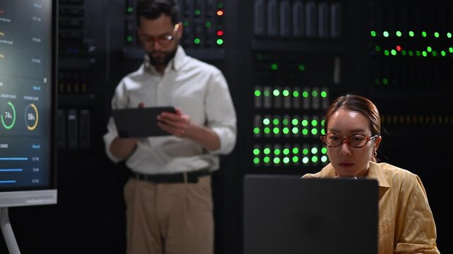 Diverse it specialists working in a data center with a server rack monitoring performance and network diagnostics