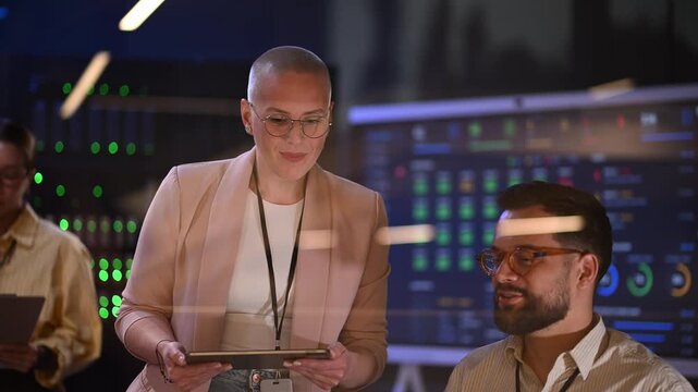 Diverse team of it professionals collaborating in a data center. Female system administrator with a tablet talking to a male programmer