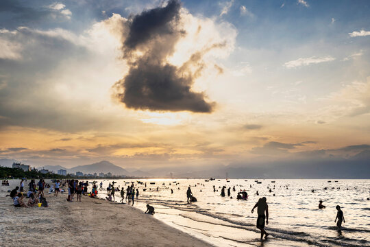 Silhouettes of bathers,swimming after sunset,in the warm sea at Da Nang Beach.