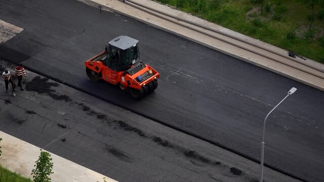 Road roller compacting fresh asphalt during urban street construction and paving works