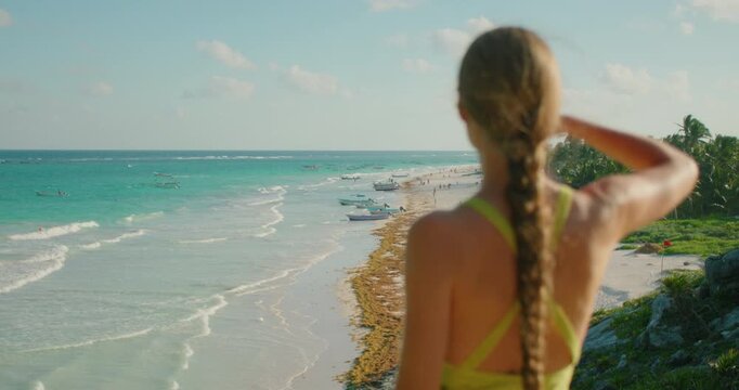 Woman with long braid looks at tropical beach Playa Santa Fe in Tulum Mexico