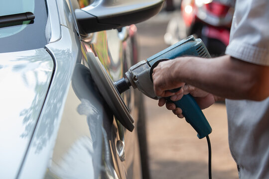 Auto Detailing Worker Polishing the Side Door Panels of a Silver Car Using an Electric Rotary Buffer Machine