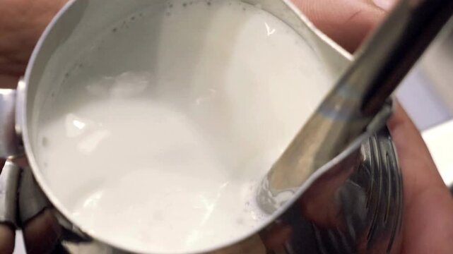 barista steaming milk with espresso machine for latte or cappuccino.