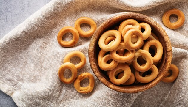 traditional italian snack taralli or tarallini in wooden bowl over light linen napkin background rustic shot of taralli appetizer with copy space top view or flat lay