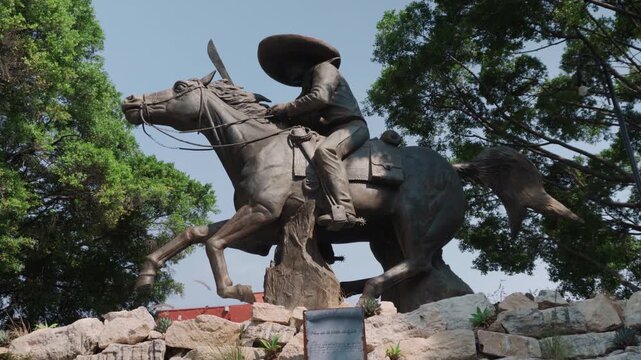 Emiliano Zapata monument in Cuernavaca framed by trees in a popular tourist area. The scene honors one of the most important figures in Mexican history and culture.