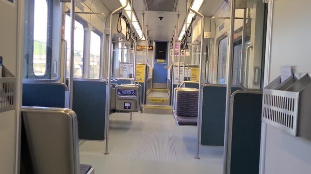 Light rail train interior with empty seat, traveling through the city during day time