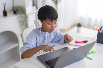 Naklejka premium Excited asian boy wearing headphones pointing at laptop screen, Concept of interactive online learning, successful e-learning education, happy student engagement and modern homeschooling concept