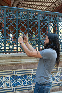 Man photographing kiosco morisco architecture with smartphone