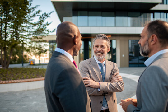 Three senior businessmen networking outside office building