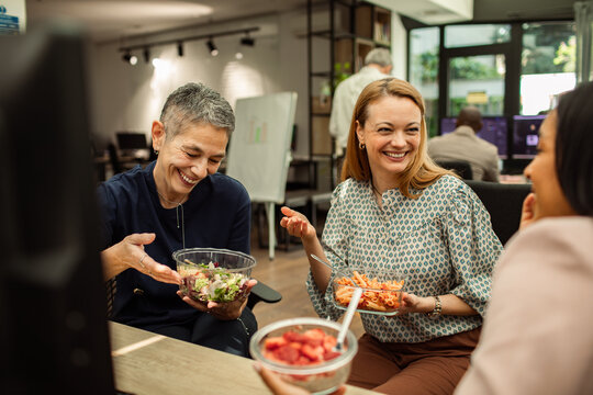 Smiling coworkers eating lunch together in modern office